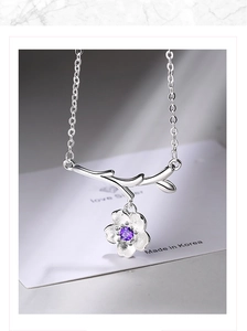 Detailed macro view of a silver cherry blossom necklace with a purple gemstone pendant