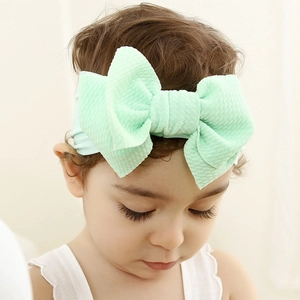 Close-up of mint green waffle fabric baby headband with a large bow on infant girl