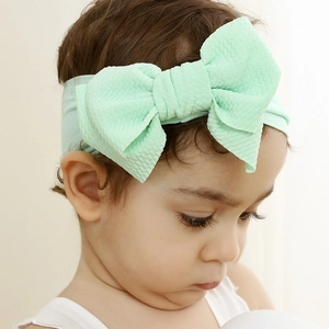 Detailed texture of mint green waffle knit nylon baby headband with a soft oversized bow
