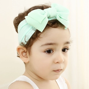 Close-up of a mint green knotted bow headband on a baby with soft waffle knit texture
