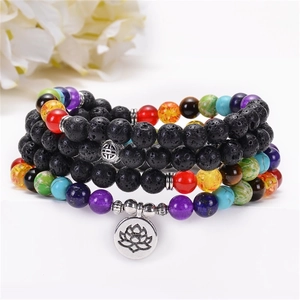 Macro detail of 108 lava stone beads with chakra colors and silver lotus yoga charm