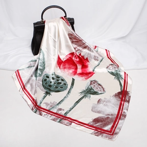 Detail of silk-like square scarf featuring lotus print draped on a black leather handbag