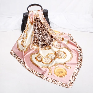Pink leopard print silk scarf draped on a black handbag with golden chain pattern