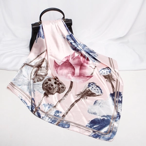 Detail of pink silk scarf with lotus print elegantly draped over a black handbag