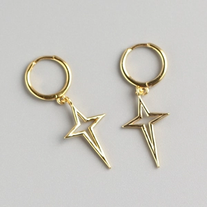Macro detail of gold North Star hoop earrings with hollow cross star charms