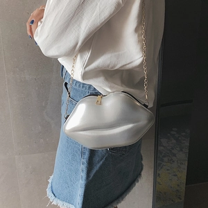 Chic silver lip-shaped crossbody bag with gold chain strap worn by a model