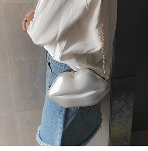 Silver lip-shaped crossbody bag with gold chain strap worn with a casual outfit