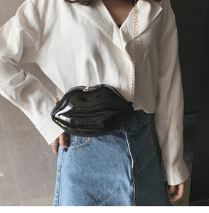 Detail of black lip-shaped crossbody bag with gold chain strap on model