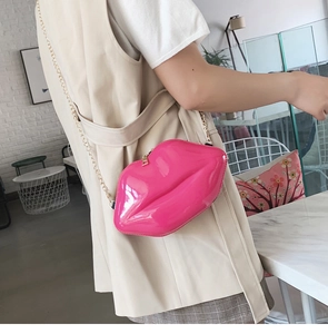 Detail of bright pink lip-shaped chain bag in glossy patent leather finish