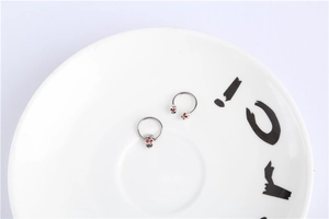 Macro view of silver punk skull body jewelry with red crystal eyes on a ceramic background