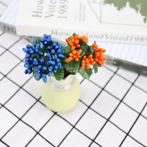 Artificial berry bouquet with blue and orange fruits in a mini vase for home decor