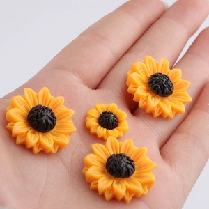 Mini resin daisy sunflowers for DIY hair accessories shown in a hand for scale