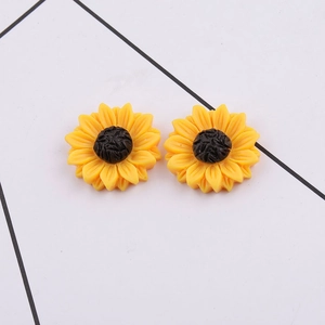 Macro view of resin daisy flower charms with yellow petals and black centers for DIY jewelry
