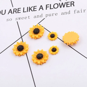 Macro shot of resin sunflower charms in two sizes with smooth flat back for DIY crafts