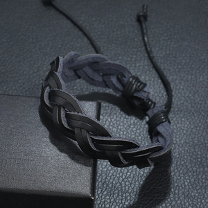 Handwoven black leather punk bracelet with adjustable cord on black textured background