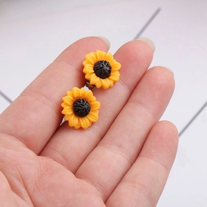 Yellow sunflower resin earrings with black center on hand, stainless steel studs