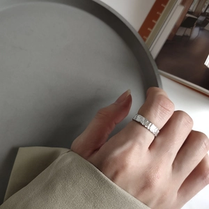 Close-up of a wide silver ring with handmade hammered texture on a model's finger