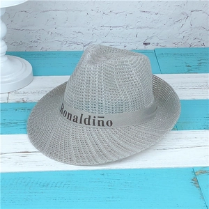 Grey woven straw fedora hat with Ronaldinho ribbon on a rustic striped background