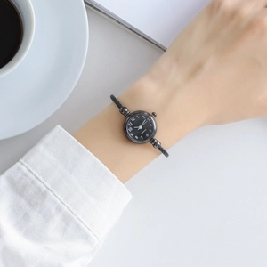 Minimalist black quartz watch with mesh strap styled with white coffee cup
