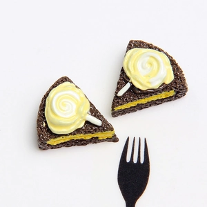 Macro shot of triangular resin chocolate cake miniatures with cream swirls and fork
