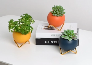 Detailed view of spherical ceramic planters with minimalist gold metal triangle stands