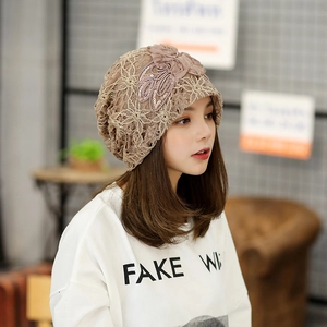 Khaki lace beanie hat with 3D silk flowers and sequins worn by model in a cafe