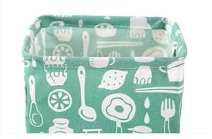 Detail of green cotton linen storage bin with white kitchen pattern and top handle