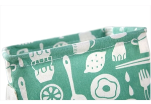 Close-up of the white stitching on a green floral canvas storage bag with handle