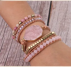 Detail of bohemian wrap bracelet with rose quartz and pink crystal beads on light wood