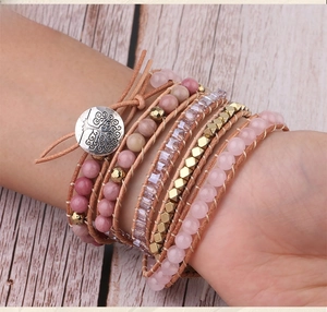 Close-up of handmade pink crystal wrap bracelet with leather cord and tree of life button