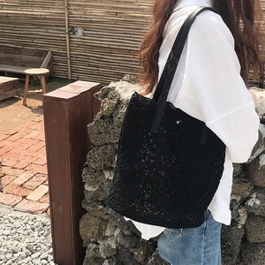 Detailed close-up of a black lace crochet tote bag with elegant hollow patterns