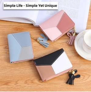 Detailed view of color-blocked leather wallets with tassel and bunny charms on wood