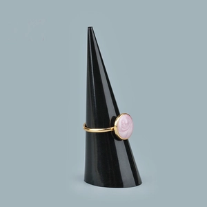 Anello dorato con vortice rosa su supporto per gioielli in acrilico nero a cono