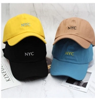 Close-up of NYC embroidered baseball caps in yellow, black, khaki, and blue colors