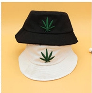 Close-up of black and white cotton bucket hats with green plant leaf embroidery
