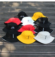Outdoor view of cotton bucket hats with embroidered text in multiple colors on wood