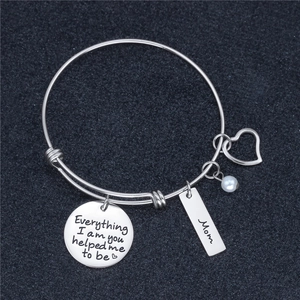 Detail of silver bangle with Mom charm, pearl, heart and inspirational quote engraving