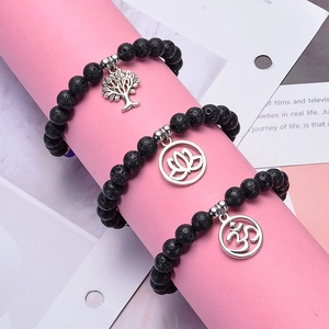 Lava rock stone bracelet with silver Tree of Life, Lotus, and Om pendants on pink display