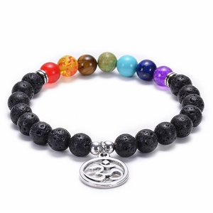 Detail of seven chakra lava rock bracelet featuring a silver Om charm and colored beads