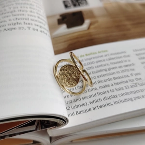 Detailed view of golden double-layer ring with vintage coin relief on a book page