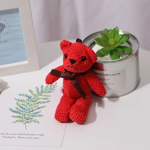 Red pineapple lattice teddy bear plush toy with brown bow tie on a minimalist desk