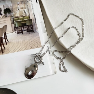 Macro detail of silver geometric pendant on Figaro chain with OT toggle clasp