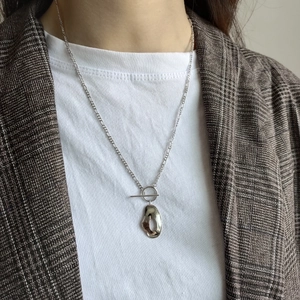 Close-up of irregular silver pendant necklace with T-bar toggle clasp on a female model