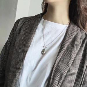 Close-up of irregular silver pendant with toggle clasp on grey plaid blazer model