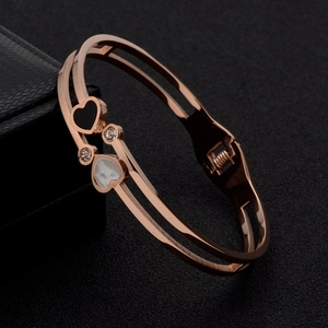 Detail of rose gold bangle featuring black and white heart shells with zircon accents