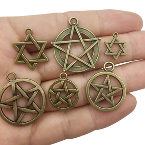Antique bronze hexagram and pentagram star charms held in hand for jewelry DIY