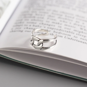 Macro shot of silver square link chain ring on book background with open band detail
