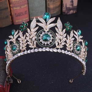 Close-up of a gold bridal crown with green and clear crystals on vintage books