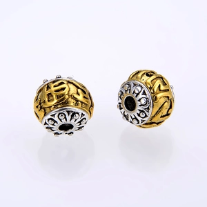 Macro detail of alloy Tibetan beads with six-word mantra and vintage silver floral caps