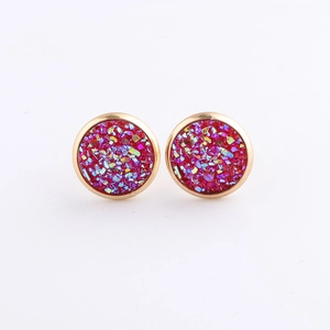 Close-up of 10mm round gold-plated stud earrings with red mineral glitter stone